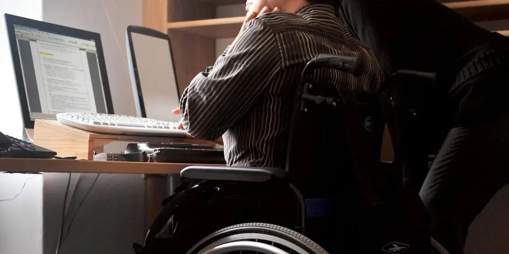 Une entrepreneuse en situation de handicap gérant ses prestations depuis son ordinateur
